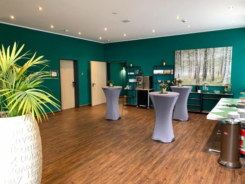 a salon with green walls and white tables and plants at Waldhotel Eskeshof in Wuppertal