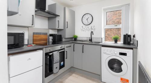 a kitchen with white cabinets and a washer and dryer at Residency apartments Sefton road in Walton on the Hill