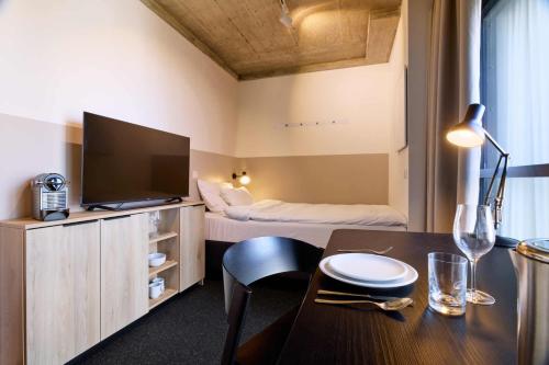 a room with a dining table with a television and a bed at District Living in Vienna