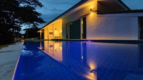 a swimming pool in front of a house at night at Mon Tresor มง เทร ซอ in Amphoe Sawang Daen Din