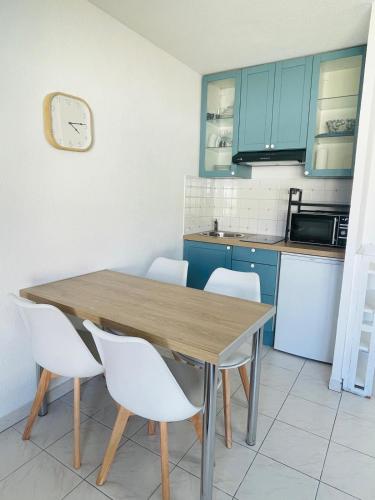 - une cuisine avec une table en bois et des chaises blanches dans l'établissement Studio climatisé - Port Fréjus, plage à 250m, à Fréjus