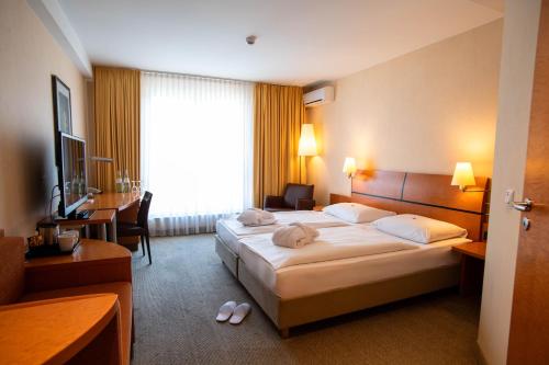 シェーネフェルトにあるBest Western Premier Airporthotel Berlinの大きなベッドと机があるホテルの部屋