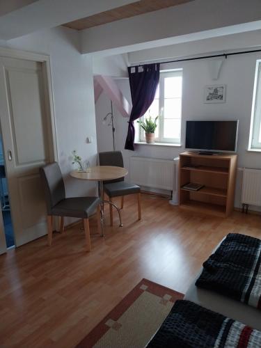 a living room with a table and chairs and a television at Tangermünde Zum S c h m u c k Giebel - Pension & FeWo in Tangermünde