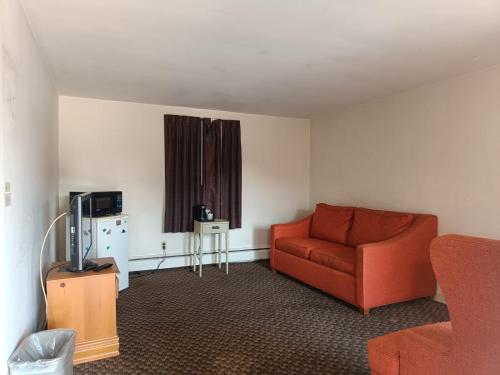 a living room with a red couch and a tv at Town & Country Inn in Seekonk
