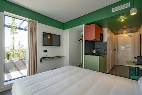 巴黎All Suites Appart Hôtel et Hôtel - Paris 13 - Porte d'Italie的带一张大床和一扇窗户的卧室