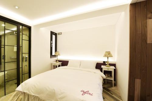 a bedroom with a white bed and two tables with lamps at Hotel Infini in Seoul