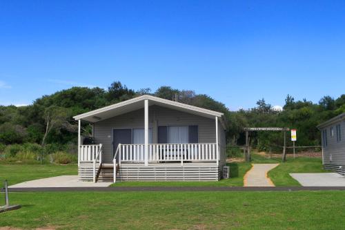 a small house with a porch on the grass at Corrimal Beach Tourist Park in Wollongong