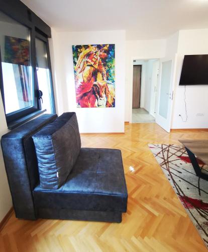 a black leather chair in a living room with a painting at The Silken Symphony in Niš