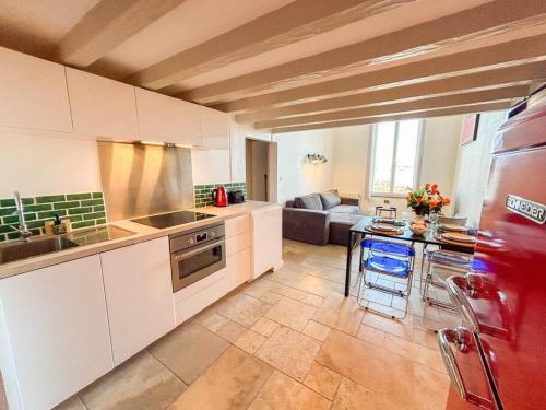 une cuisine avec des armoires blanches et un salon dans l'établissement Duplex port de Sanary - Vue mer, à Sanary-sur-Mer