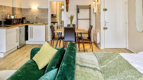 un salon avec un canapé vert et une cuisine dans l'établissement Le Loft Boucherat - Hypercentre - 2 pers, à Troyes