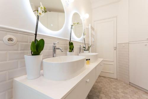 - une salle de bains blanche avec deux lavabos et deux miroirs dans l'établissement Maison Josephine Stunning Apartment Champs-Elysees 3 bedrooms, à Paris