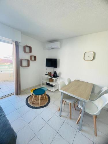 un salon avec une table, des chaises et une télévision dans l'établissement Studio climatisé - Port Fréjus, plage à 250m, à Fréjus