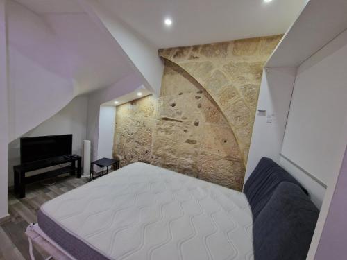 une chambre avec un lit et un mur en pierre dans l'établissement Studio Fontaine Musicale, à Béziers