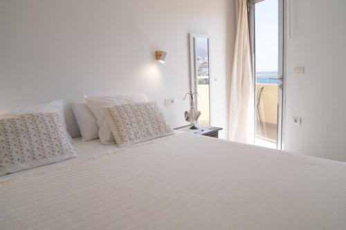 a white bed with white pillows and a window at Holiday House Aguacate 2 in San Sebastián de la Gomera