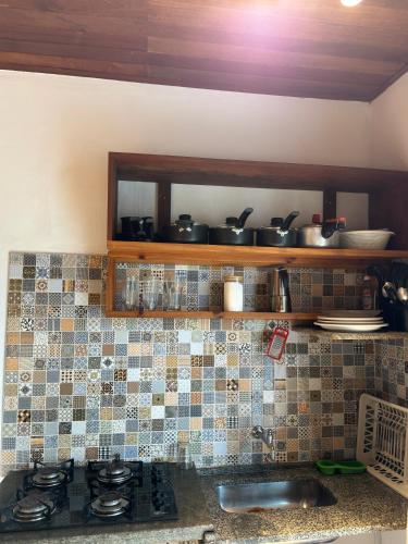 a kitchen with a sink and a counter with pots and pans at Pituba Vile - Apartamento Mandala in Itacaré