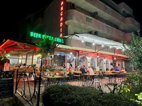 people sitting at tables outside a restaurant at night at Arkadia Guest House in Primorsko