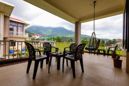 a porch with chairs and a table and a swing at Vista Valley Stay, Luxury 3 BHK Villa Kangra, Dharamshala in Dharamshala