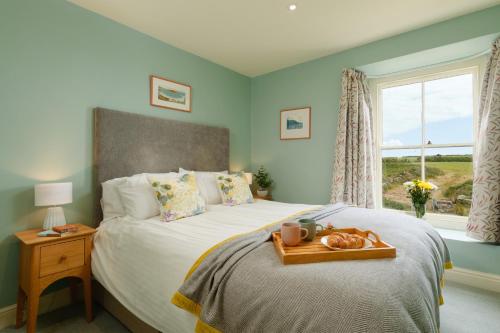 a bedroom with a bed with a tray of bread on it at Bosistow Farmhouse in Penzance