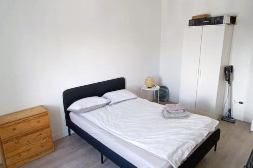 Cette chambre comprend un lit avec des draps blancs et une commode. dans l'établissement Home Sweet Home, à Aubervilliers