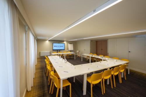 a large conference room with a long table and yellow chairs at Mercure Perpignan Centre in Perpignan