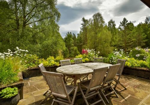 a wooden table and chairs in a garden at Cairngorm Lodge Rothiemurchus in Aviemore