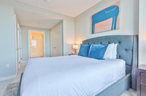 a bedroom with a large white bed with blue pillows at Luxury Apt with Water Views in Boston