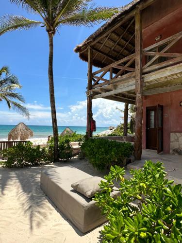 a bed on the beach next to a building at La Conchita Tulum in Tulum