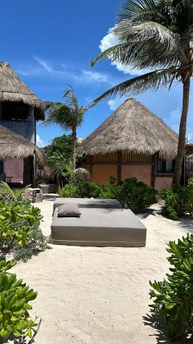 a bed on the sand in front of a resort at La Conchita Tulum in Tulum
