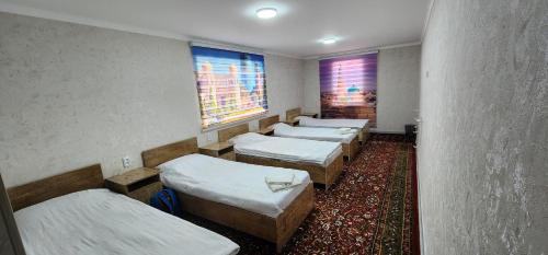 a row of beds in a room with a carpet at Deshon Qala Guest House in Khiva