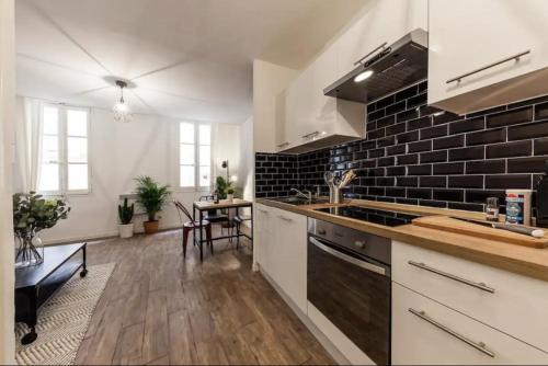 une cuisine avec des placards blancs et un mur en briques noires dans l'établissement Charmant appartement au panier 1ER, à Marseille