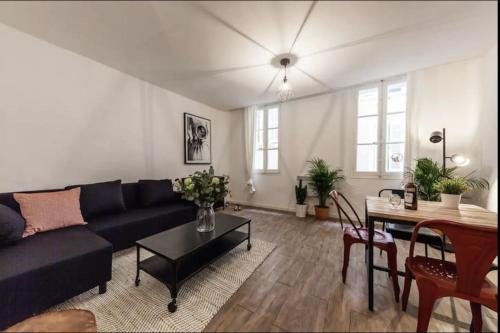 un salon avec un canapé noir et une table dans l'établissement Charmant appartement au panier 1ER, à Marseille