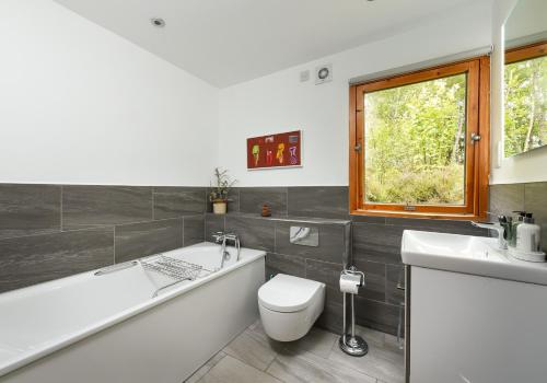 a bathroom with a tub and a toilet and a sink at Cairngorm Lodge Rothiemurchus in Aviemore