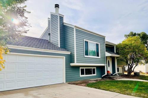 a blue house with a white garage at Bright Home - Huge Backyard 20 min - Denver & Boulder in Broomfield