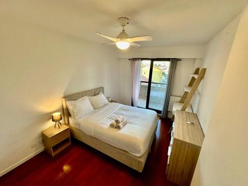 a bedroom with a bed with a ceiling fan and a window at ⁂ Charmant 2 pièces centre-ville avec parking in Cagnes-sur-Mer