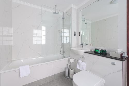 a white bathroom with a shower and a toilet and a sink at Gem Fitzrovia Hotel in London