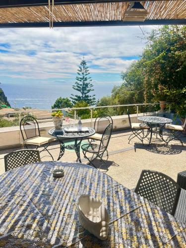 un patio con tavoli, sedie e vista sull'oceano di Villa La Perla Capri a Capri
