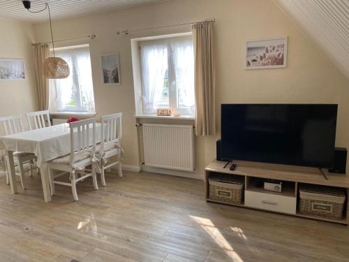 Una sala de estar con un televisor y una mesa con sillas. en Küstenglück Sylt D1, en Westerland
