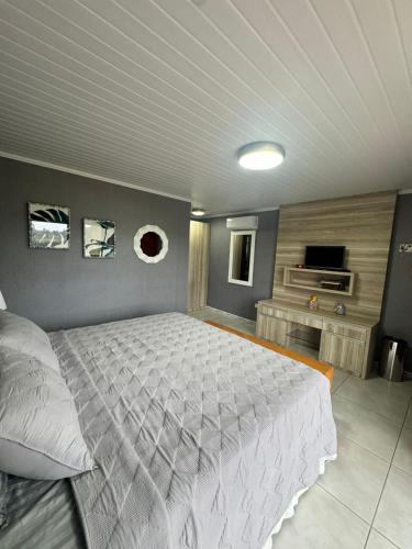 a bedroom with a large bed and a flat screen tv at Chalés Marrevi HomeHotel in São José dos Pinhais