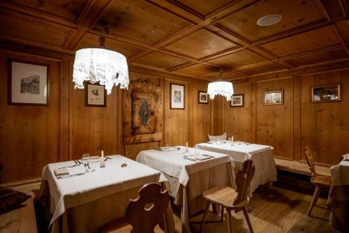 a dining room with two tables and chandeliers at Sporthotel Teresa in Badia