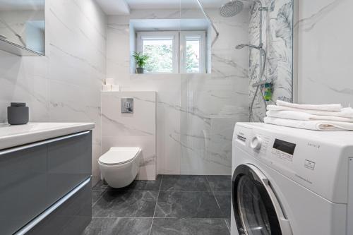 a white bathroom with a washing machine in it at Apartament Emily Brzeźno in Zaspa