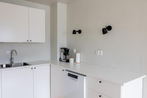 Una cocina blanca con gabinetes blancos y un fregadero. en Riverside Suites by BookLapland, en Rovaniemi