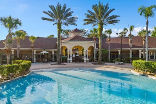 a swimming pool in front of a building with palm trees at 3BD/3BA Windsor Hills, 10 min to Disney in Orlando