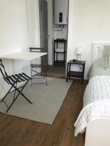 a room with a table and a chair and a bed at Chambre du Haras Cour Lozey in Sainte-Marguerite-des-Loges