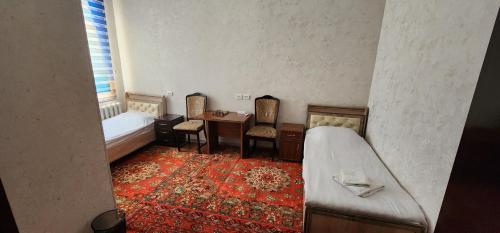 a bedroom with a bed and a desk and a table at Deshon Qala Guest House in Khiva