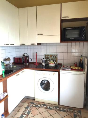 une cuisine avec un lave-linge et un micro-ondes dans l'établissement Vague Blu, à Nice