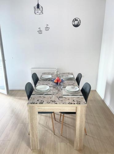 a dining room table with chairs and a wooden table with plates and glasses at Apartman Danijela in Popovača