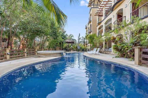 a pool with blue water in front of a building at Gav10 Modern Pool Side Condo in Quiet Area of Tam in Tamarindo
