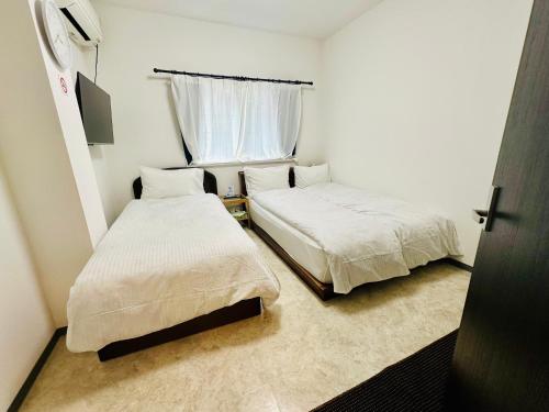 Una pequeña habitación con dos camas y una ventana. en Yokohama Paradise203, en Yokohama