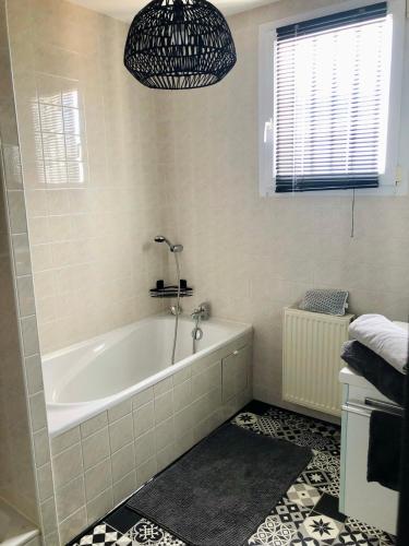 a bathroom with a bath tub and a window at Espace deux chambres et sanitaires in Puilboreau