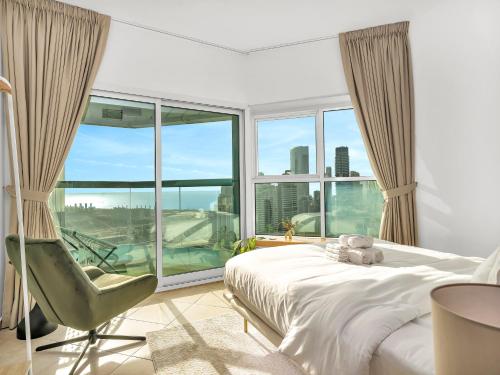 a bedroom with a bed and a chair and a large window at Stunning Panoramic Sea & Marina Skyline View in Dubai